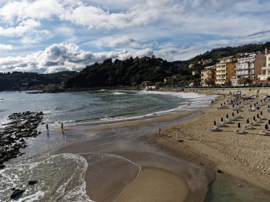  Yazın arka planda kıyı şeridi olan Şairler Körfezi 'nin deniz kıyısında güneşli şemsiyeli ve şezlonglu kumsal manzarası yükseldi.