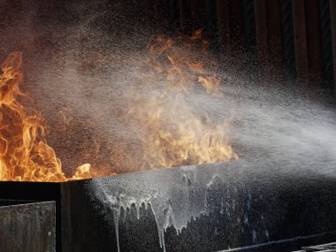 İnsanlar su ile yangın söndürme alıştırması yapıyorlar..