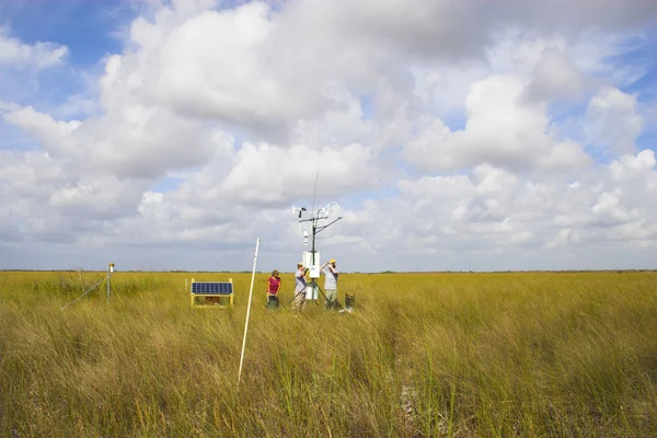 Cientistas instalando instrumentos científicos no campo de grama — Fotografia de Stock