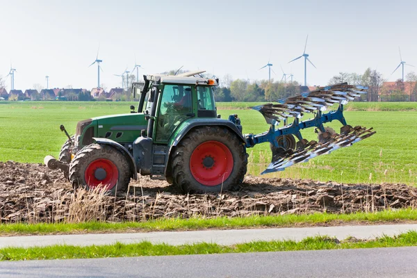 Traktor med plowes på fältet våren. — Stockfoto