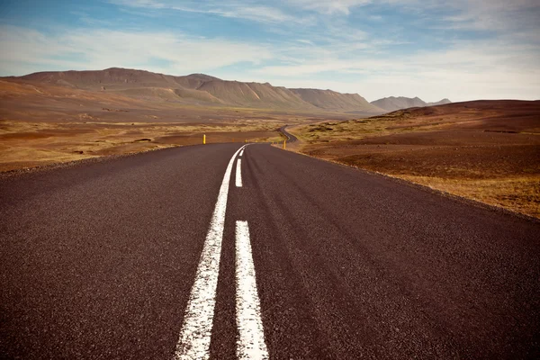 Highway through dry gravel lava field landscape under a blue sum — Stock Photo, Image