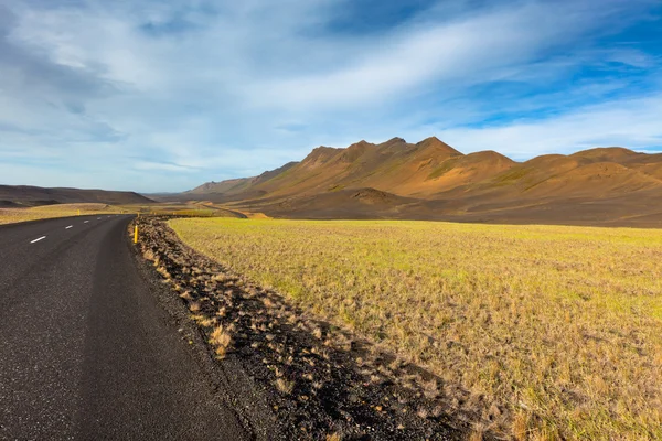 Carretera a través de Islandia campo paisaje bajo un cielo azul de verano . —  Fotos de Stock