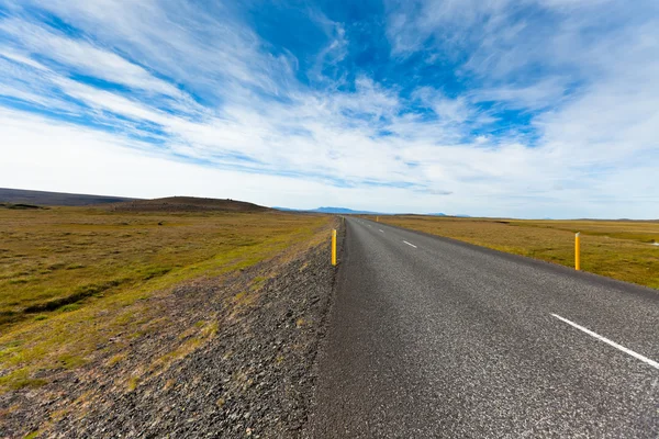 Autostrada attraverso il paesaggio islandese sotto un cielo blu estivo con — Foto Stock