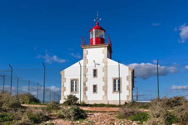 Bright Lighthouse beyond chain link fence — Stock Photo, Image