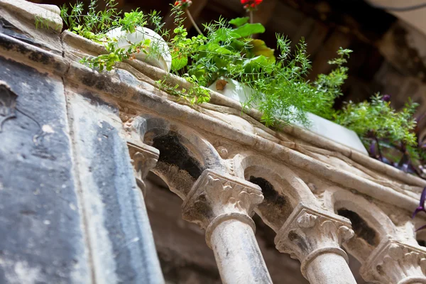 Régi kő erkély falfelületeken, zöld növényekkel — Stock Fotó