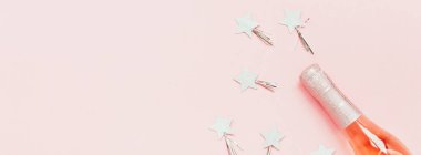 Noel ya da yeni yıl kompozisyonu. İçinde gül şampanyası şişeleri ve pastel pembe arka planda parlak parlak yıldız konfetileri var. Kutlama düzlüğü. Parti yaratıcı kavramı