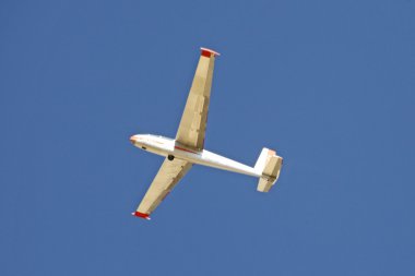 Glider flying on a blue sky clipart