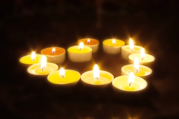 Grupo de velas encendidas sobre fondo negro. — Foto de Stock