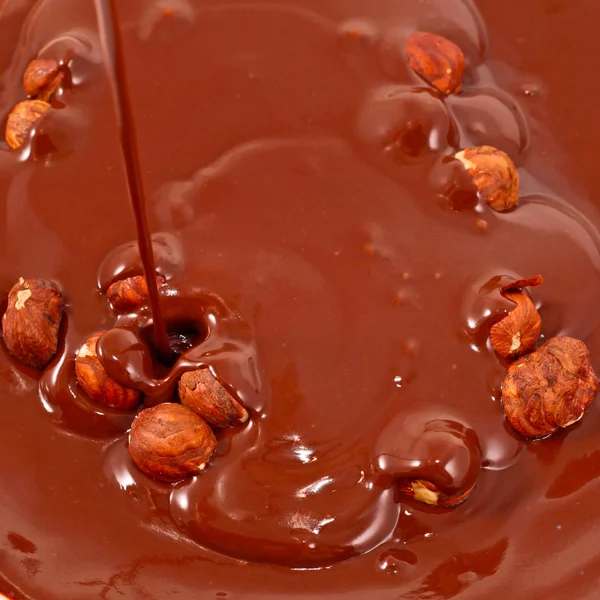 Chocolate flui em nozes. Olhar saboroso - fundo de comida abstrata — Fotografia de Stock