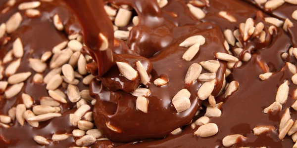 Pouring hot melted chocolate with sunflower seeds — Stock Photo, Image