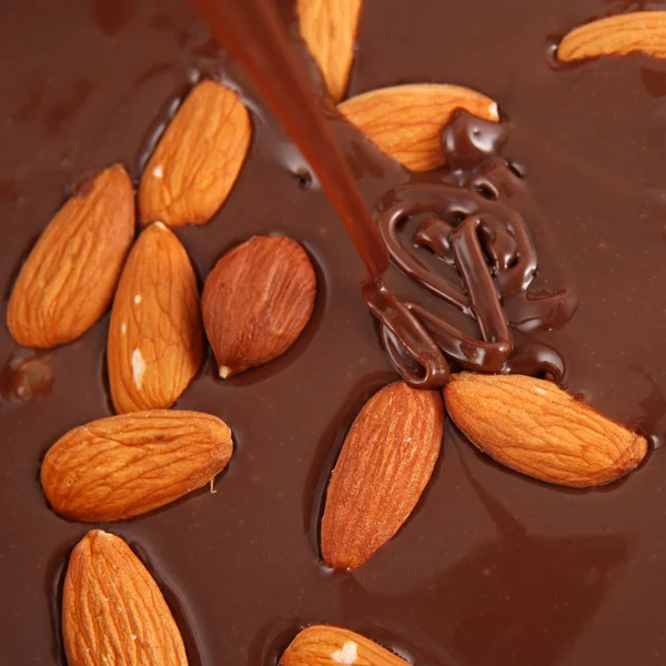 Pouring hot melted chocolate and almond nuts — Stock Photo, Image