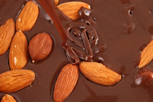 Pouring hot melted chocolate and almond nuts — Stock Photo, Image