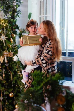 Küçük kız ve annesi Noel ağacının yanında.