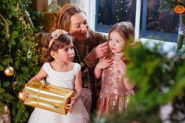Noel ağacının yanında annesi olan küçük bir kız.