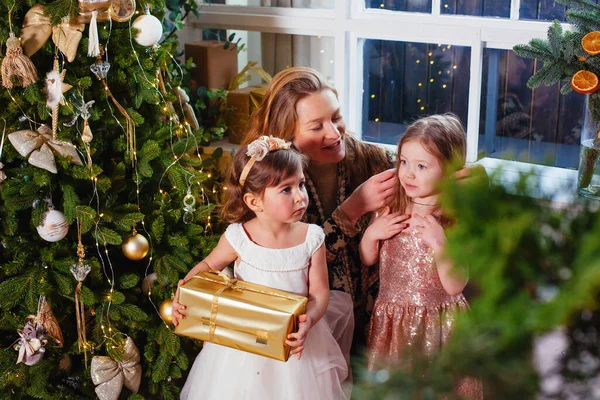 Noel ağacının yanında annesi olan küçük bir kız.