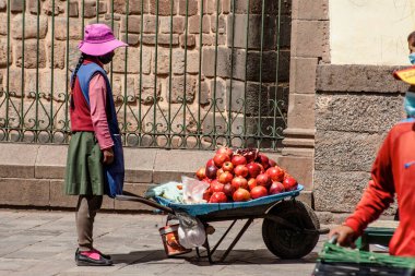 Peru - 15 Mayıs 2022: Cuzco 'da geleneksel giyinmiş Perulu insanlar. Sokakta nar satan bir kız. Cusco, Peru, 15 Mayıs 2022