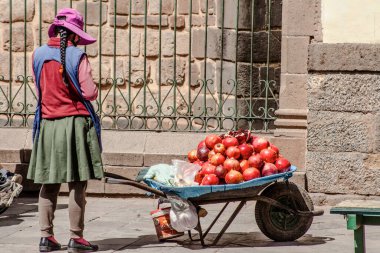 Peru - 15 Mayıs 2022: Cuzco 'da geleneksel giyinmiş Perulu insanlar. Sokakta nar satan bir kız. Cusco, Peru, 15 Mayıs 2022