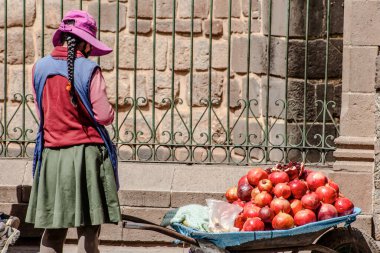 Peru - 15 Mayıs 2022: Cuzco 'da geleneksel giyinmiş Perulu insanlar. Sokakta nar satan bir kız. Cusco, Peru, 15 Mayıs 2022