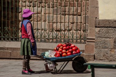 Peru - 15 Mayıs 2022: Cuzco 'da geleneksel giyinmiş Perulu insanlar. Sokakta nar satan bir kız. Cusco, Peru, 15 Mayıs 2022