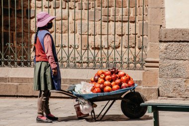 Peru - 15 Mayıs 2022: Cuzco 'da geleneksel giyinmiş Perulu insanlar. Sokakta nar satan bir kız. Cusco, Peru, 15 Mayıs 2022