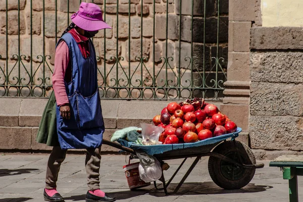 Peru - 15 Mayıs 2022: Cuzco 'da geleneksel giyinmiş Perulu insanlar. Sokakta nar satan bir kız. Cusco, Peru, 15 Mayıs 2022