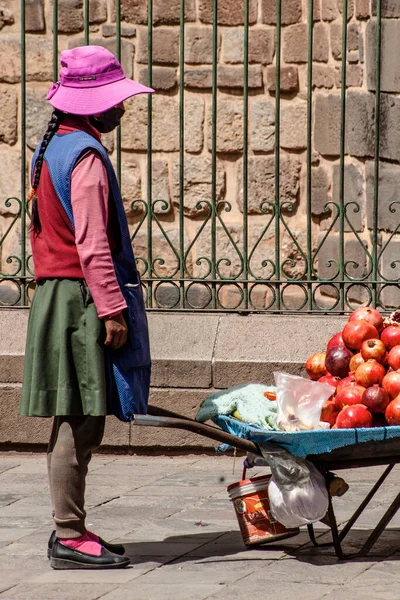 Peru - 15 Mayıs 2022: Cuzco 'da geleneksel giyinmiş Perulu insanlar. Sokakta nar satan bir kız. Cusco, Peru, 15 Mayıs 2022