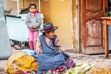 PERU - MAY 5, 2022: Peruvian people in traditional clothes in Ollataytambo. Woman selling on the street in Ollataytambo, Peru, May 5, 2022