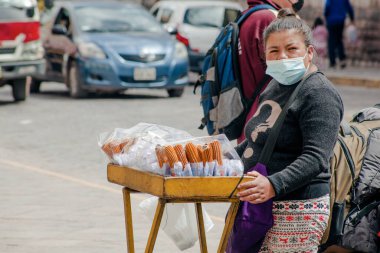Peru - 15 Mayıs 2022: Cuzco 'da geleneksel giyinmiş Perulu insanlar. 15 Mayıs 2022 'de Cusco, Peru' da geleneksel yemek churros 'u yapan kadın.