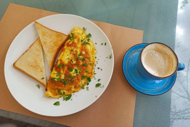 Breakfast served on the table, omelet with toasts and coffee