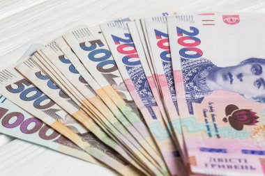 Ukrayna 'nın parası. Beyaz ahşap masanın üzerinde ellerinde bir yığın Ukrayna Hryvnia banknotları. Hryvnia 200 ve 500