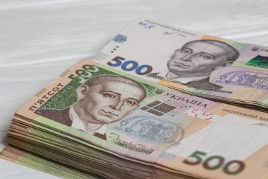 Ukrayna 'nın parası. Beyaz ahşap masanın üzerinde ellerinde bir yığın Ukrayna Hryvnia banknotları. Hryvnia 200 ve 500