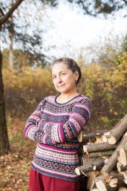 Sonbahar manzarasının arka planında süveter giymiş güzel yaşlı kadın portresi. 