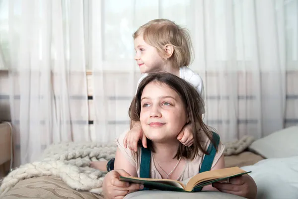 Hermana Más Joven Sentada Espalda Mayor Abrazándola Mientras Lee Libro — Foto de Stock