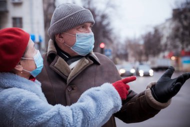 Coronavirus kuantini sırasında kışın sokakta maskeli yaşlı bir çift.
