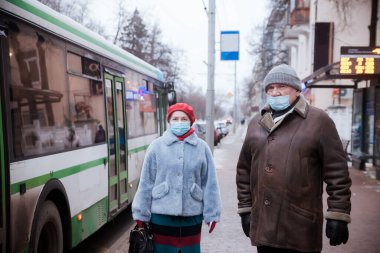 Coronavirus kuantini sırasında kışın sokakta maskeli yaşlı bir çift.