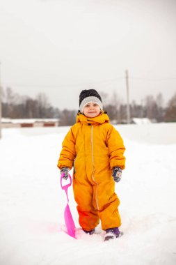 Portrait of   little three-year-old girl in   winter jumpsuit on   walk in winter. 