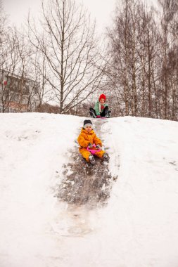 Happy children riding down   ice slide on   sled