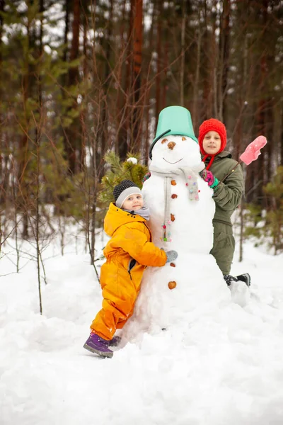 Children of nine and three years old   on   winter walk near   snowman 