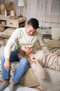 Portrait of   beautiful Russian couple in sweaters on   bed at home.