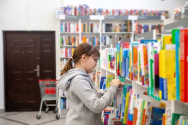 Portrait of   eleven - year - old teenage girl in   bookstore . 