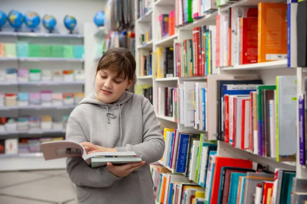 Teenage Girl Gray Hoodie Choosing Books Store — стоковое фото