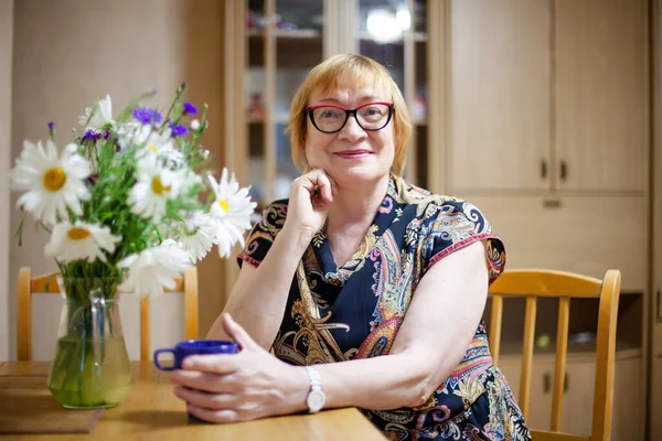 家の中で生きている野花の花束を持つ高齢女性 — ストック写真