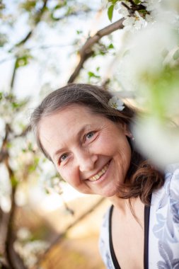 Baharın çiçek açan bahçelerinin arka planında açık renk elbiseli güzel bir kadının portresi..