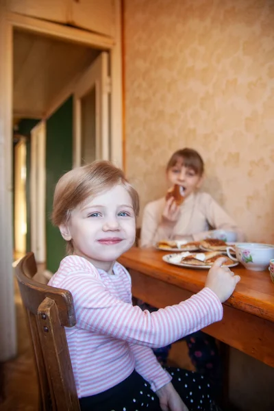 Hároméves Lány Asztalnál Húgával Palacsintával Reggelizik Tejföllel — Stock Fotó