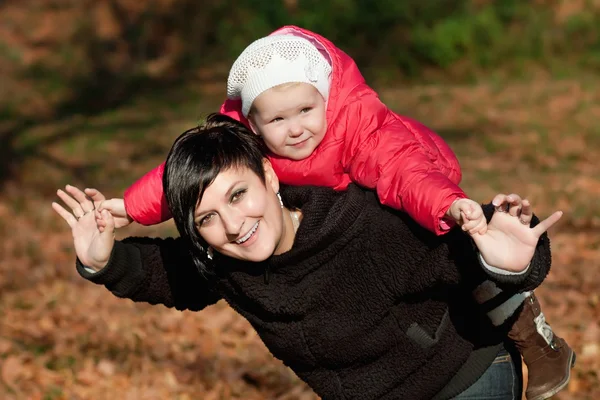 Jonge moeder en haar peuter meisje veel plezier in de herfst — Stockfoto