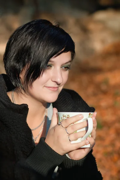 Młoda kobieta trzymając kubek herbaty odkryty — Zdjęcie stockowe