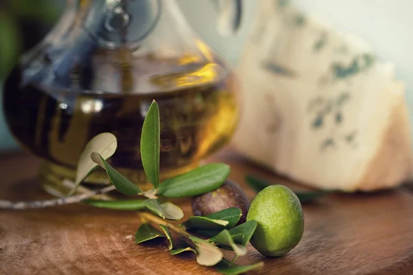 Butelka oliwy z oliwek na starym drewnianym stole i serze — Zdjęcie stockowe