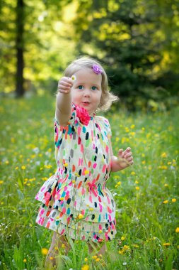 bir çayır çiçeklerle dolu, sevimli küçük kız