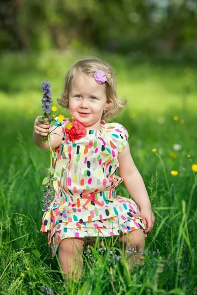 Милая маленькая девочка на лугу, полном цветов — стоковое фото