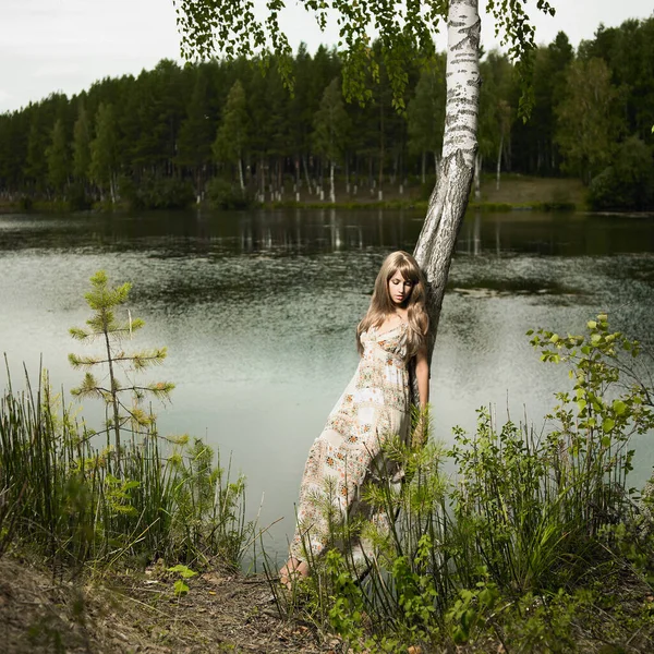 ドレスを着た若い美しいブロンドが森の中を歩いている ヌード女性は自然の中で立つ — ストック写真